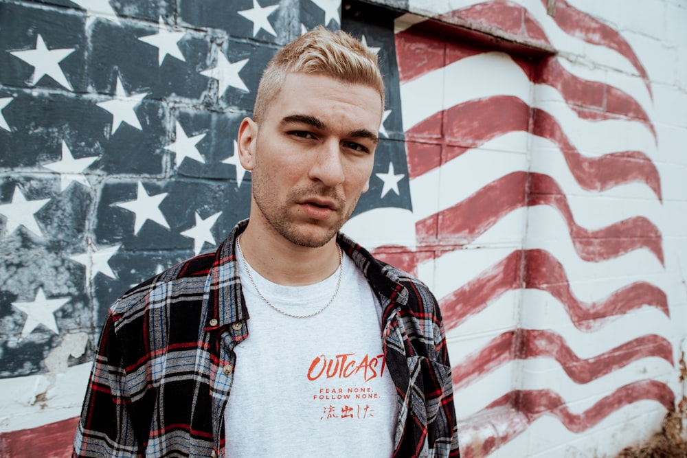 man standing in front of U.S.A. flag graffiti