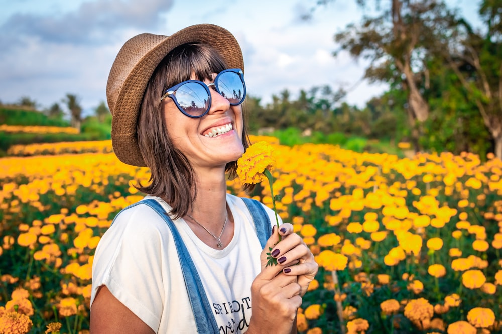 woman in white shirt smiling near flower garden
