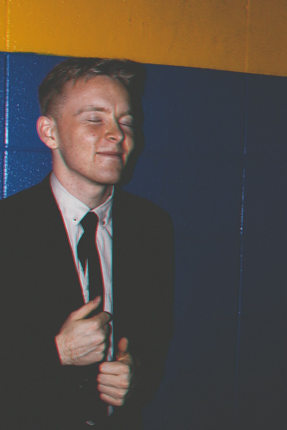 man wearing suit beside wall