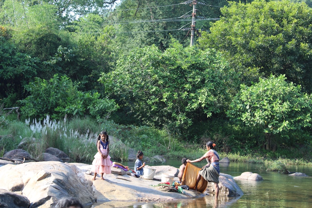 people sitting on rock beside body of water during daytiem