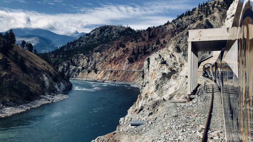 railroad beside body of water in between mountains