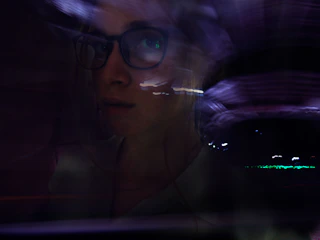A gritty, high-contrast portrait of zxoe bathed in electric blue light with glitch effects distorting the edges.