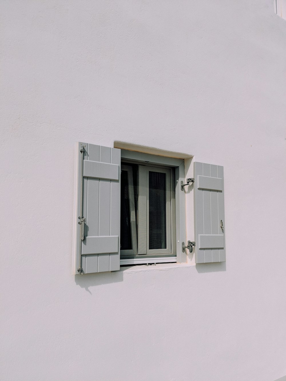 Panneau de fenêtre à battant en bois gris dans un bâtiment en béton blanc