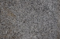 A close-up of a textured granite surface featuring a mix of gray, black, and subtle brown speckles.