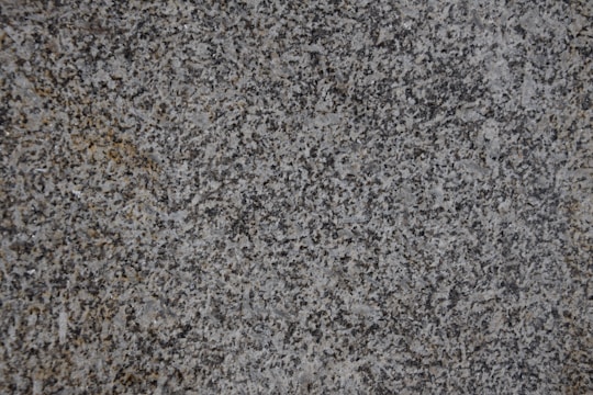 A close-up of a textured granite surface featuring a mix of gray, black, and subtle brown speckles.