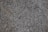 A close-up of a textured granite surface featuring a mix of gray, black, and subtle brown speckles.
