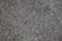 A close-up of a textured granite surface featuring a mix of gray, black, and subtle brown speckles.
