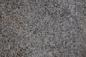 A close-up of a textured granite surface featuring a mix of gray, black, and subtle brown speckles.