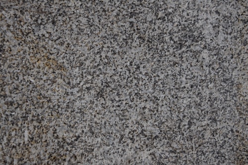 A close-up of a textured granite surface featuring a mix of gray, black, and subtle brown speckles.