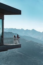 Elegant concierge handing over keys in a stylish Grenoble apartment with Alpine mountains visible through the window.
