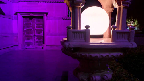 A towering door with pulsating purple light beams, standing in a futuristic cityscape.