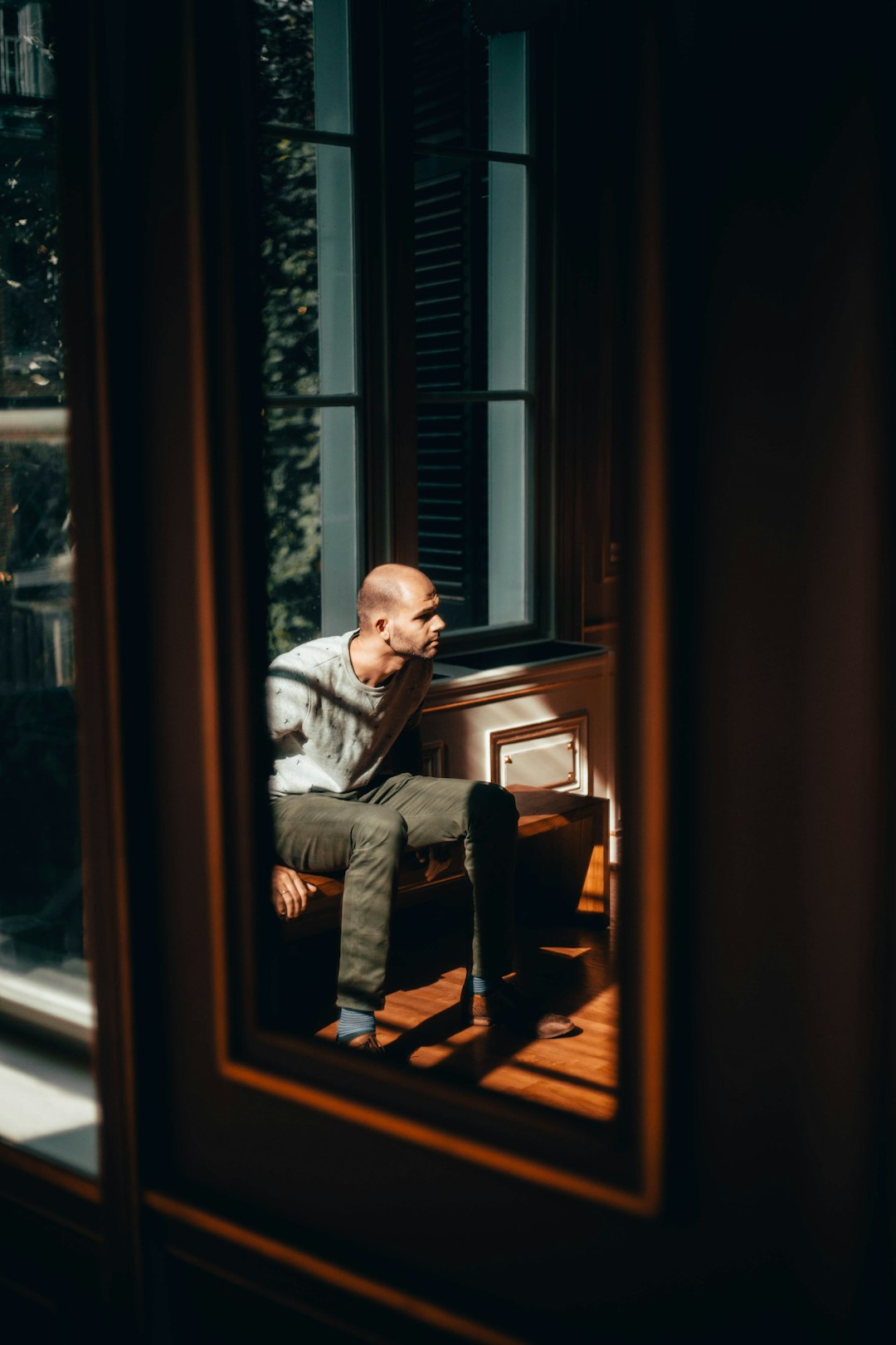 man sitting against window near mirror