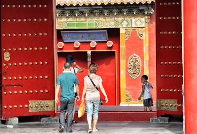 three people walking toward red building