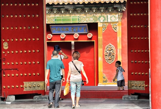 three people walking toward red building in The Palace Museum China