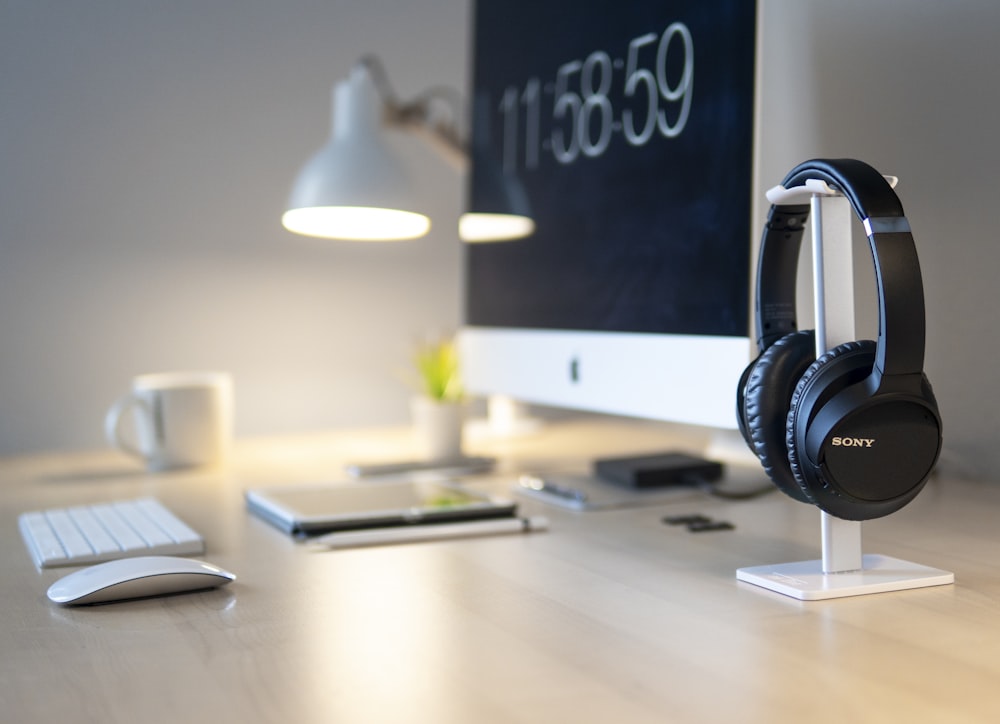black Sony headphones beside iMac on clean workspace