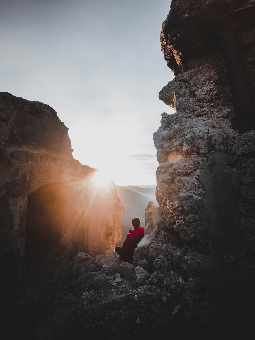 man sitting between rock formation during daytime