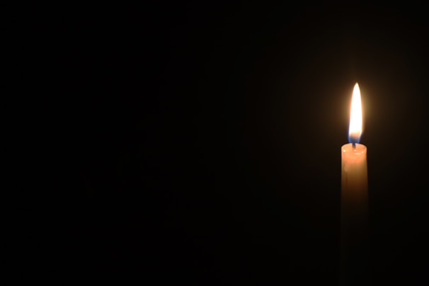 A glowing candle illuminating a dark room.