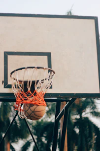 A basketball hoop with an orange ball mid-air, about to score.