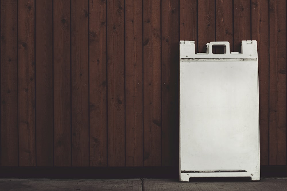 uma geladeira branca sentada em frente a uma parede de madeira