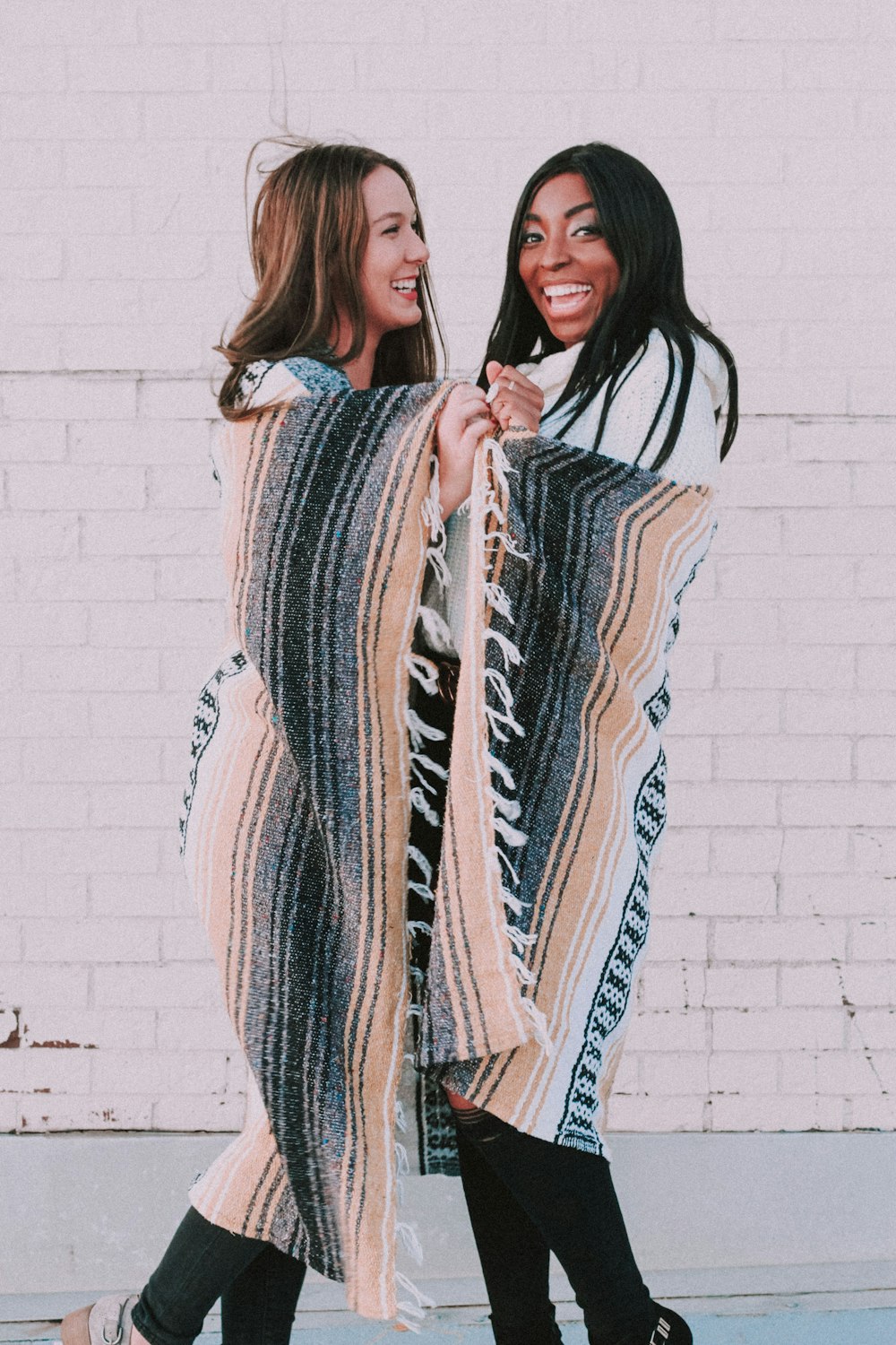 man and woman standing and covering blanket and smiling