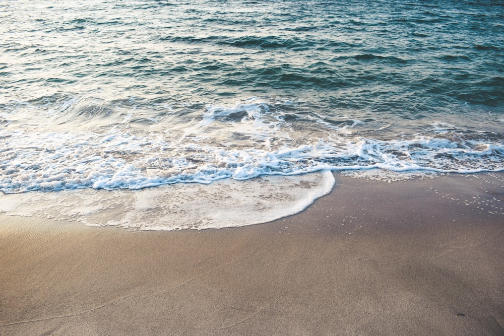 waves crashing shore during daytime