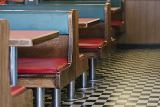 A cozy vintage diner interior with black walls, orange neon lights, and a juicy burger with a thick milkshake on a wooden table.