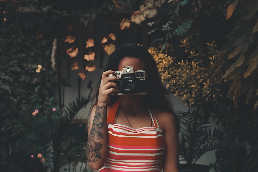 woman holding camera beside trees