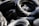 A pile of tires is covered in a light dusting of snow, highlighting their curved surfaces and textured treads. The shadows and snow create a contrast that emphasizes the black rubber and white snow.