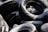 A pile of tires is covered in a light dusting of snow, highlighting their curved surfaces and textured treads. The shadows and snow create a contrast that emphasizes the black rubber and white snow.