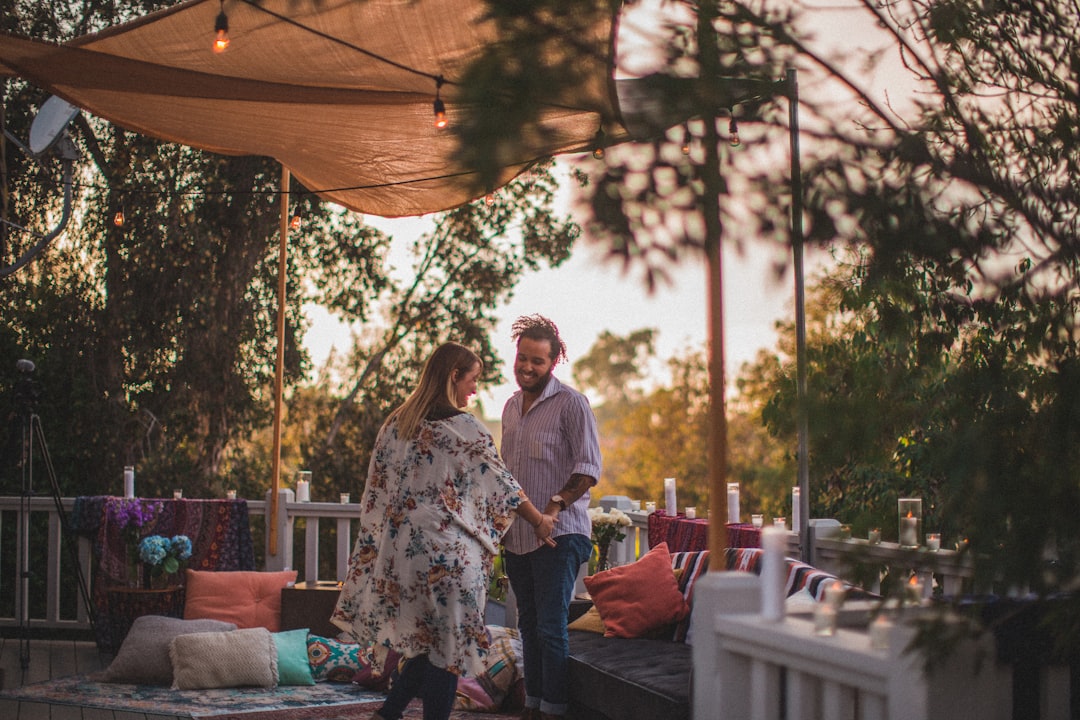 man and woman standing beside sofa while holding hands