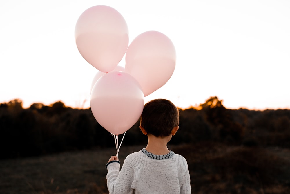 boy holding pink balloons