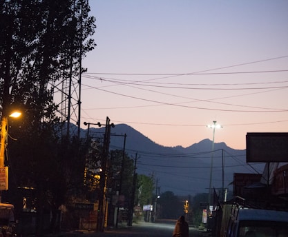 A quiet street at dusk, shadows stretching long as the city hums softly beneath a fading sky.