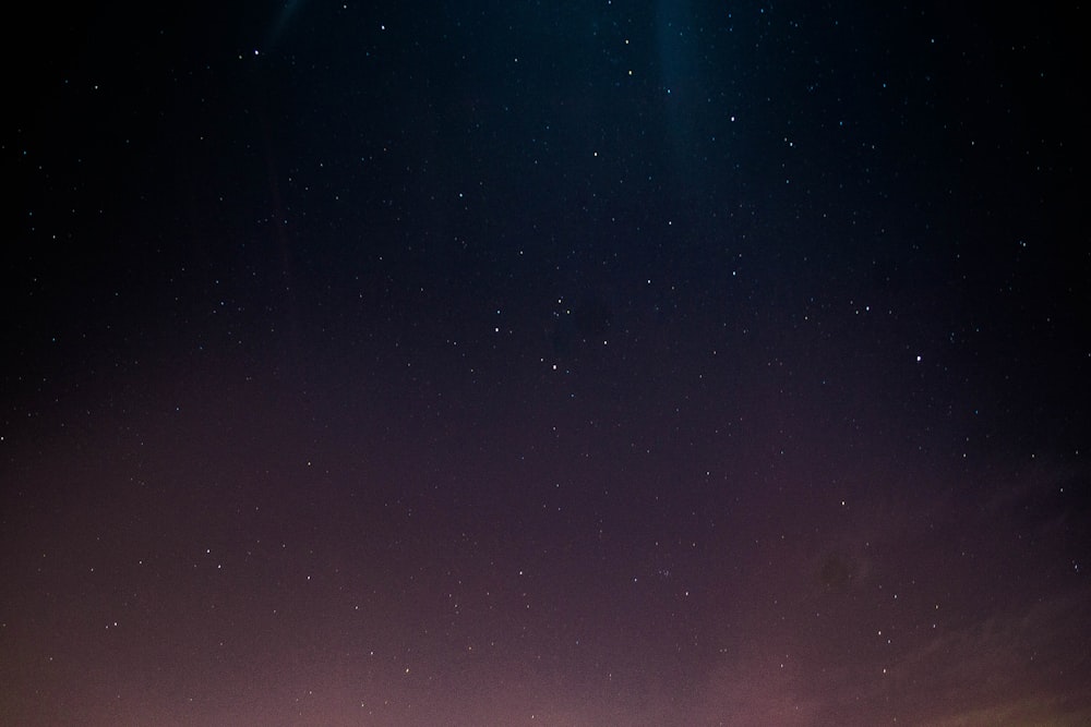 a couple of people standing on top of a hill under a sky filled with stars