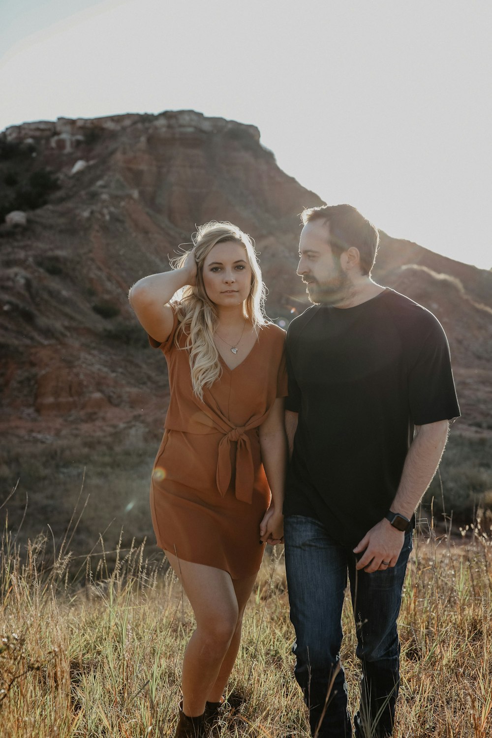 Homem e mulher de mãos dadas no campo de grama durante o dia