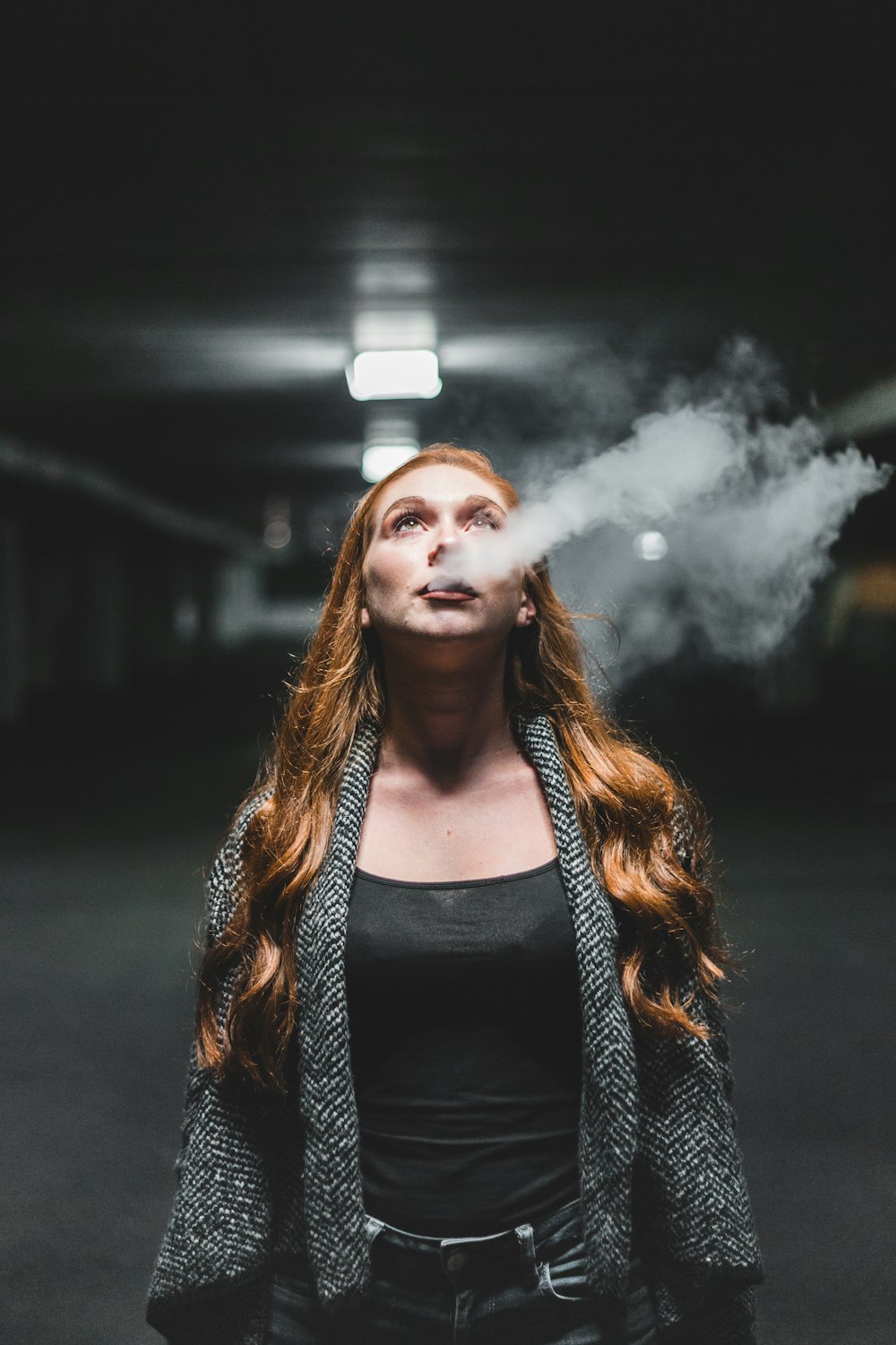 Frau schaut auf, während sie Rauch bläst