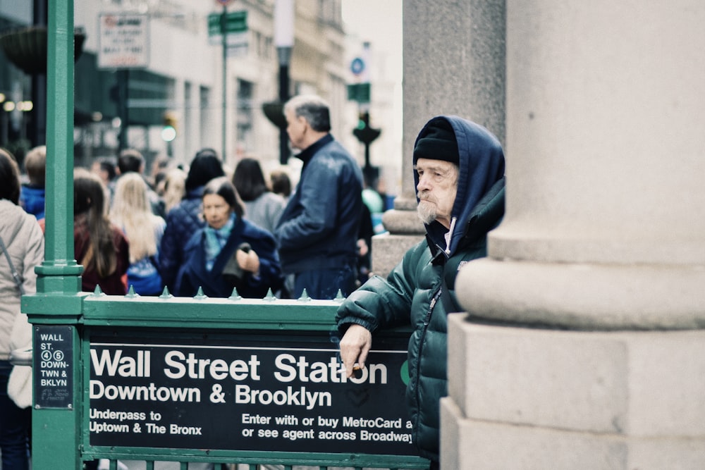 un uomo sconosciuto in piedi accanto allo stato di Wall Street in centro e all'insegna di Brooklyn