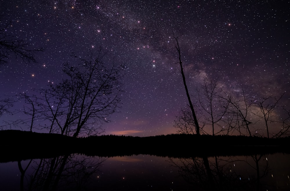 lake beside silhouette of mountain during nighttime