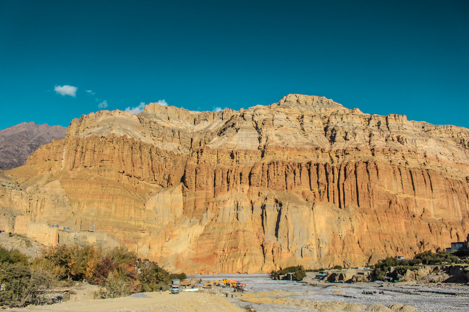 Towering ochre wind-carved cliffs of the Mustang badlands glowing gold under a deep blue sky
