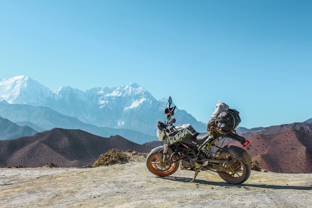 black and gray backbone motorcycle parked outdoor with mountain at distance during daytime