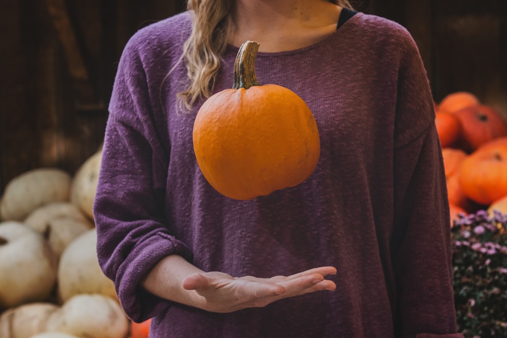 woman in purple shirt holding pumpkin