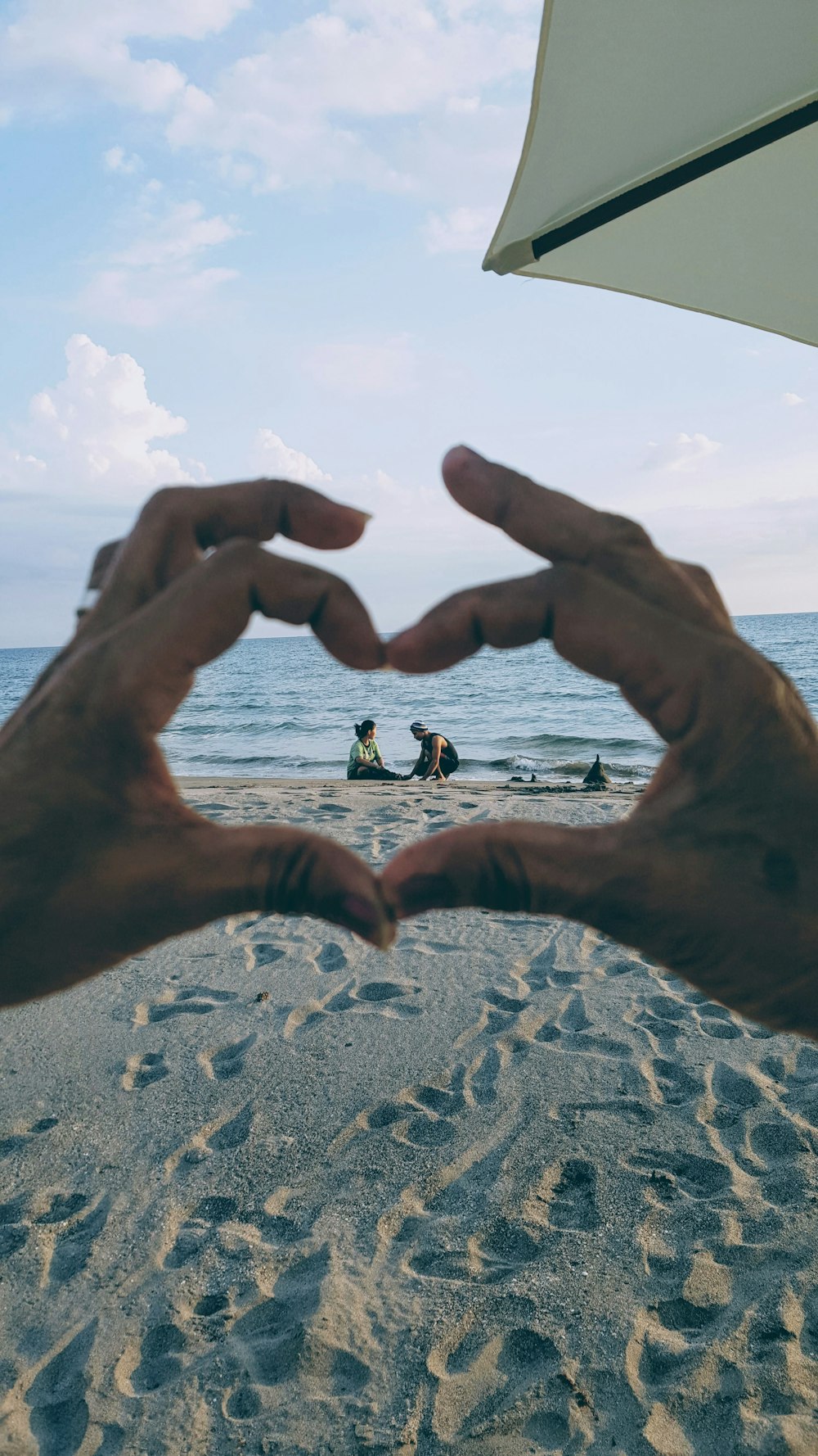 two persons sitting on sand during daytime