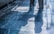 The image features two individuals with only their lower bodies visible. They are standing on a shiny, polished stone floor with visible reflections and shadows. There are cleaning supplies, including a mop and a bottle, placed against the wall on the left side of the image.