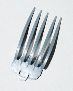 A close-up view of a metallic clipper guard attachment displaying multiple evenly spaced prongs. The number '2' is printed on the base, indicating its size measurement.