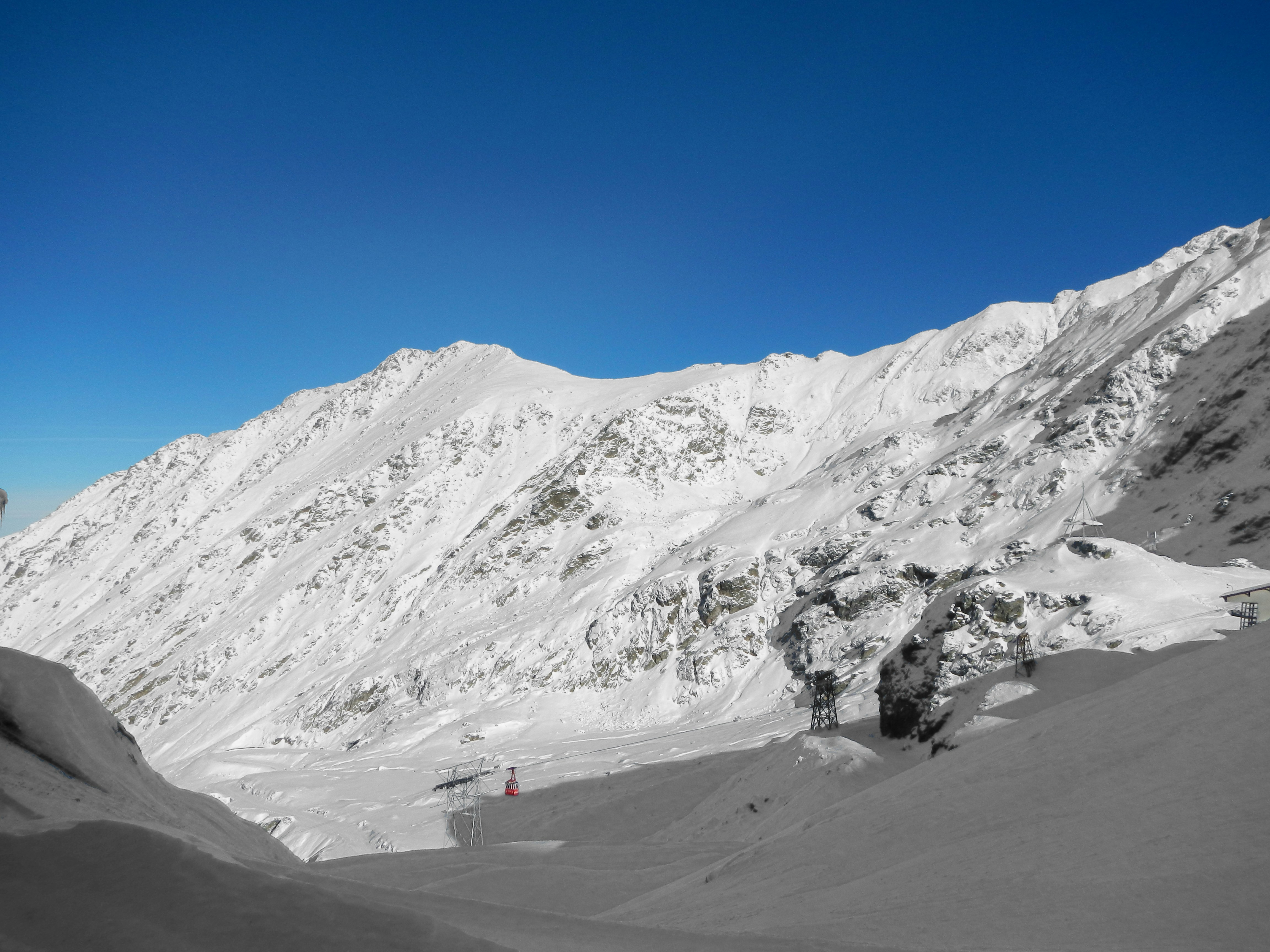 Red cable car in snow covered mountains