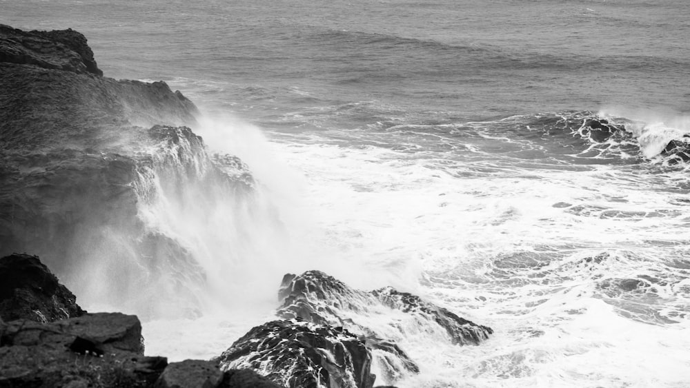 grayscale photography of sea water and rock formation