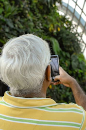 man holding smartphone near green plants