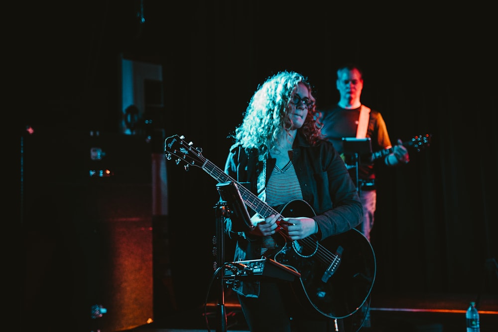 person in black blazer playing Les Paul guitar performing on stage