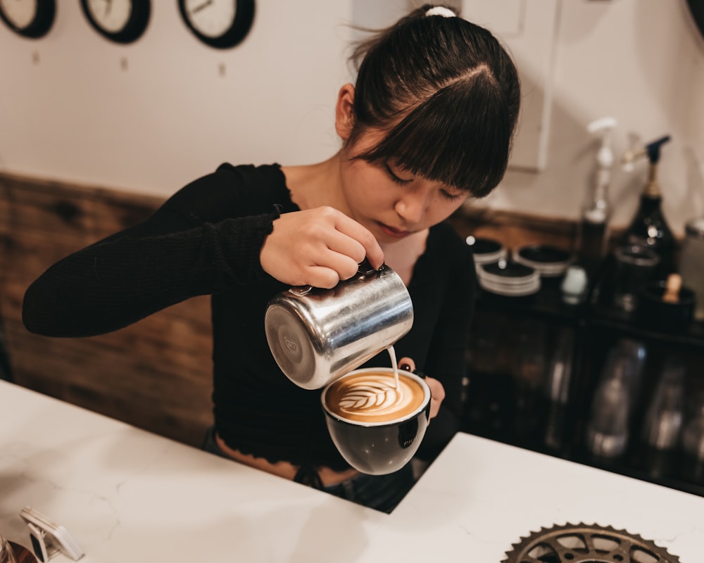 woman pouring cream on mug inside bar