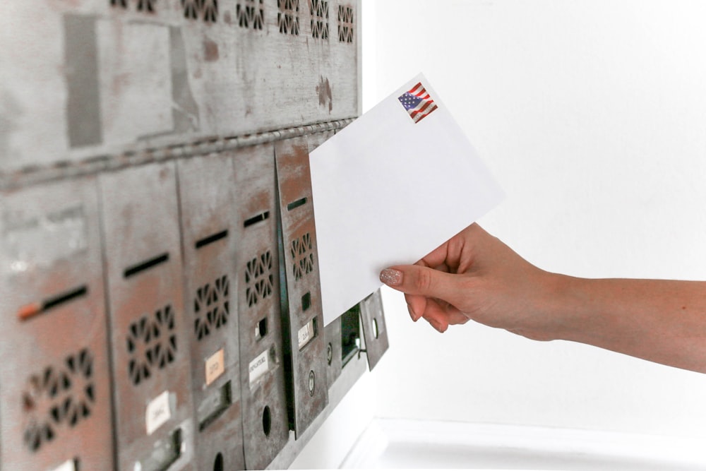 Person mit Postumschlag legt Karton auf
