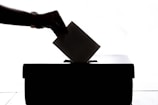 a person is casting a vote into a box